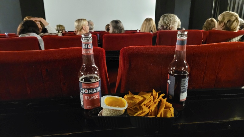 Kinosaal, Getränke und Nachos auf der Ablage in den Sitzreihen