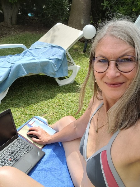 Selfie einer Frau in Bikini mit Laptop auf einer Liege