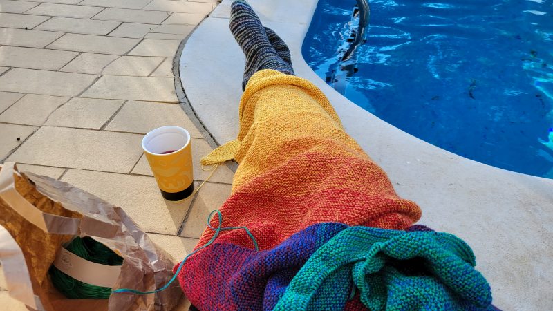 Frau mit Strickzeug auf den Beinen - Farbverlaufsgarn in allen Regenbogenfarben