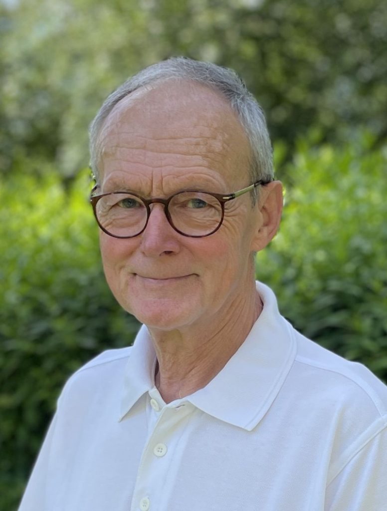 Andreas Hufschmidt Autorenporträt, älterer Herr mit Brille in weißem Poloshirt lächelt vor grünem Hintergrund