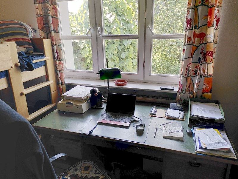 alter Schreibtisch mit Schreibutensilien vor einem Fenster