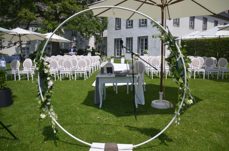 Sicht durch den Traubogen der draußen vorbereiteten Freien Hochzeit im Garten des Hofguts Besselich